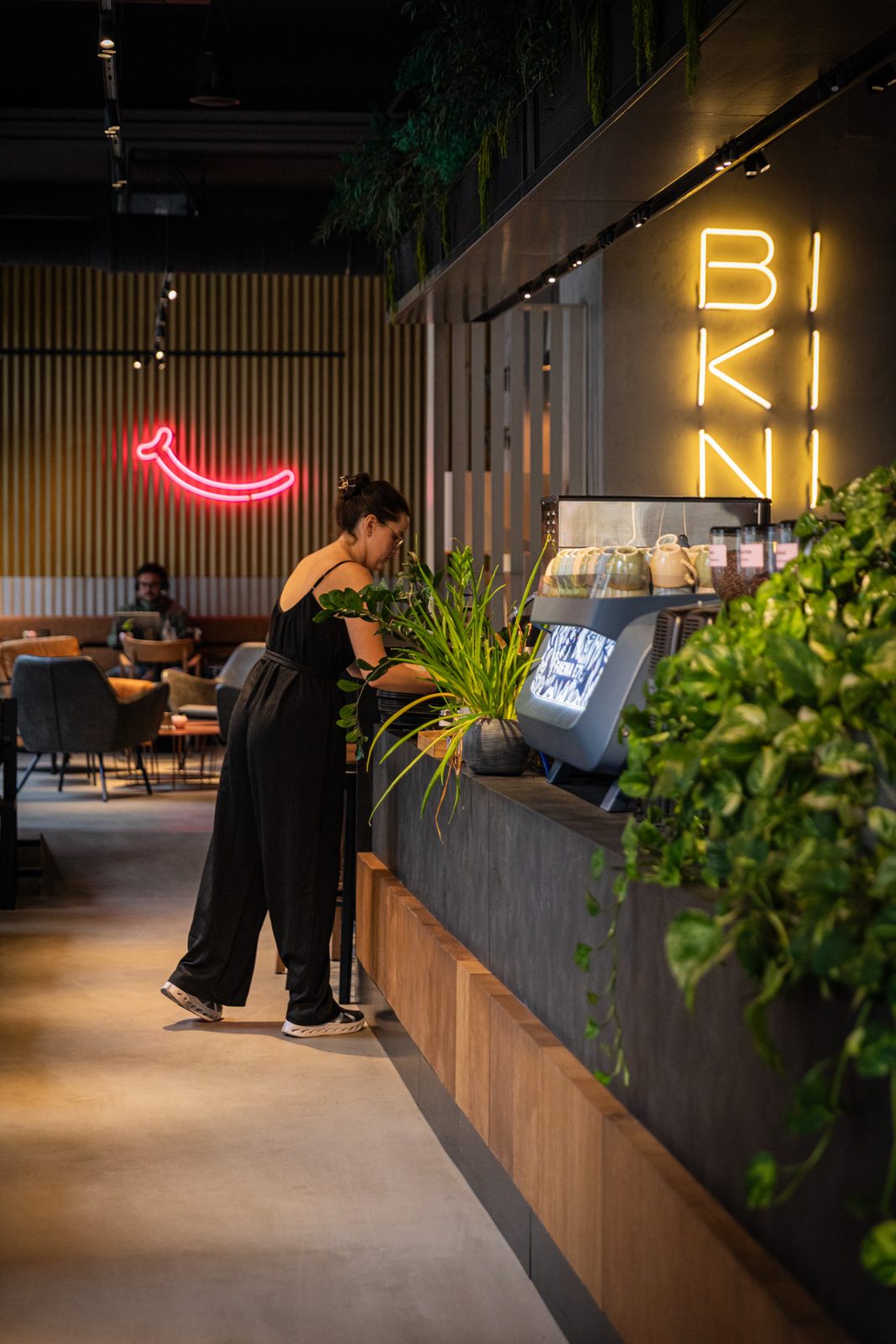 Barista an der Siebträgermaschine vor dem leuchtenden BIKINI-Neon