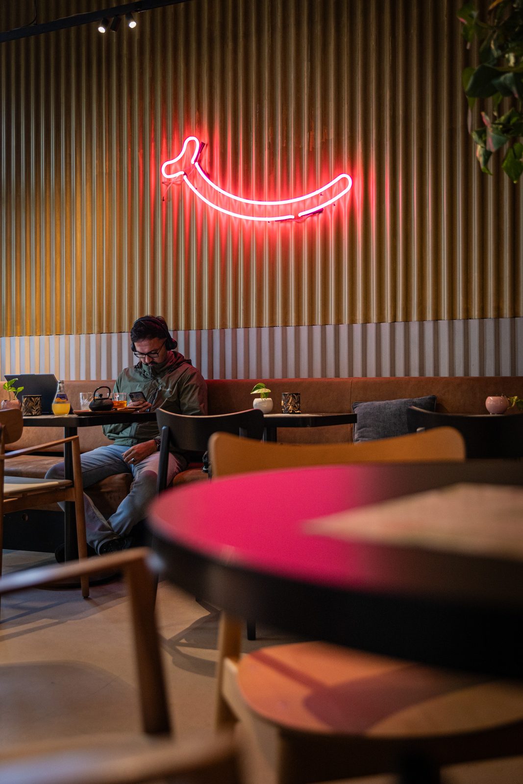 Roter Neon-Smiley über gemütlichen Tischen im BIKINI